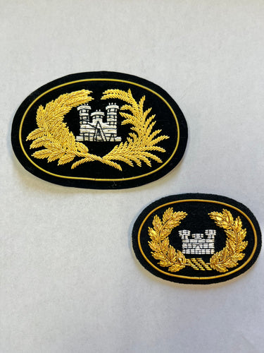 Large and small oval patch with black background, gold border, gold leaves and gray castle in the center